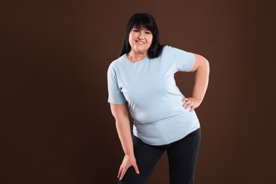Photo of Beautiful overweight mature woman with charming smile on brown background