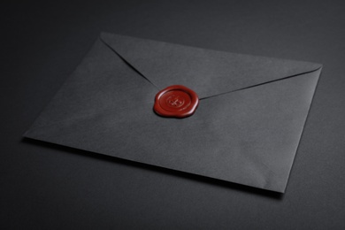 Photo of Envelope with wax seal on black background