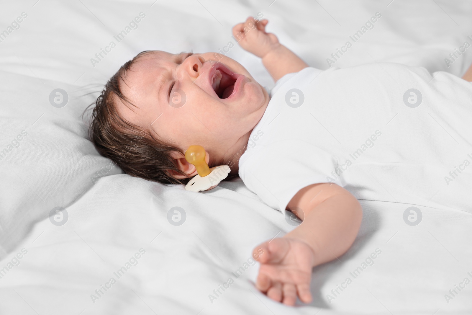 Photo of Cute little baby crying on soft bed