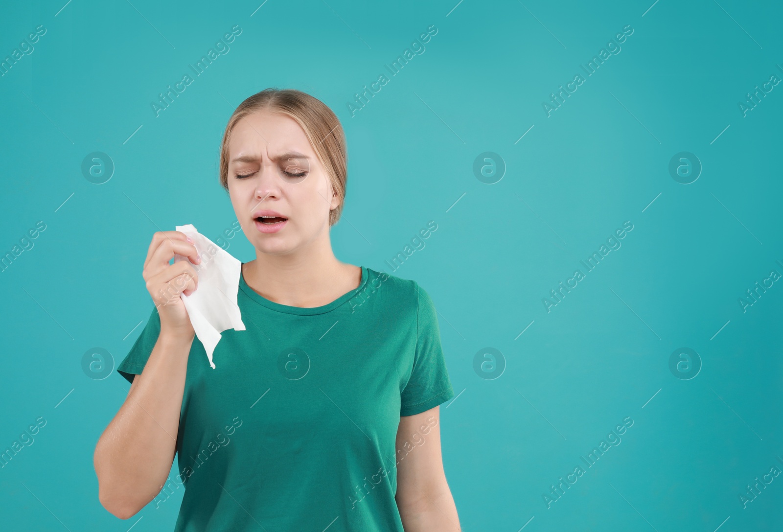 Photo of Young woman suffering from allergy on turquoise background. Space for text