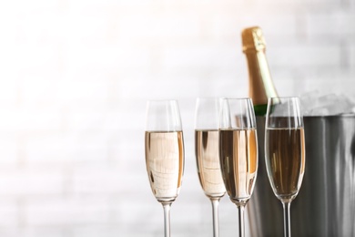 Glasses with champagne and bottle in bucket against blurred background. Celebration time