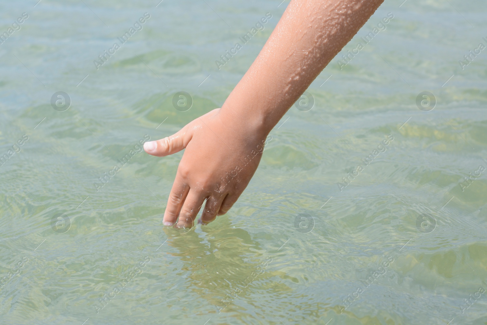 Photo of Kid touching cool clear water outdoors, closeup