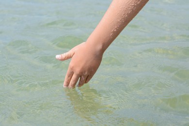 Photo of Kid touching cool clear water outdoors, closeup