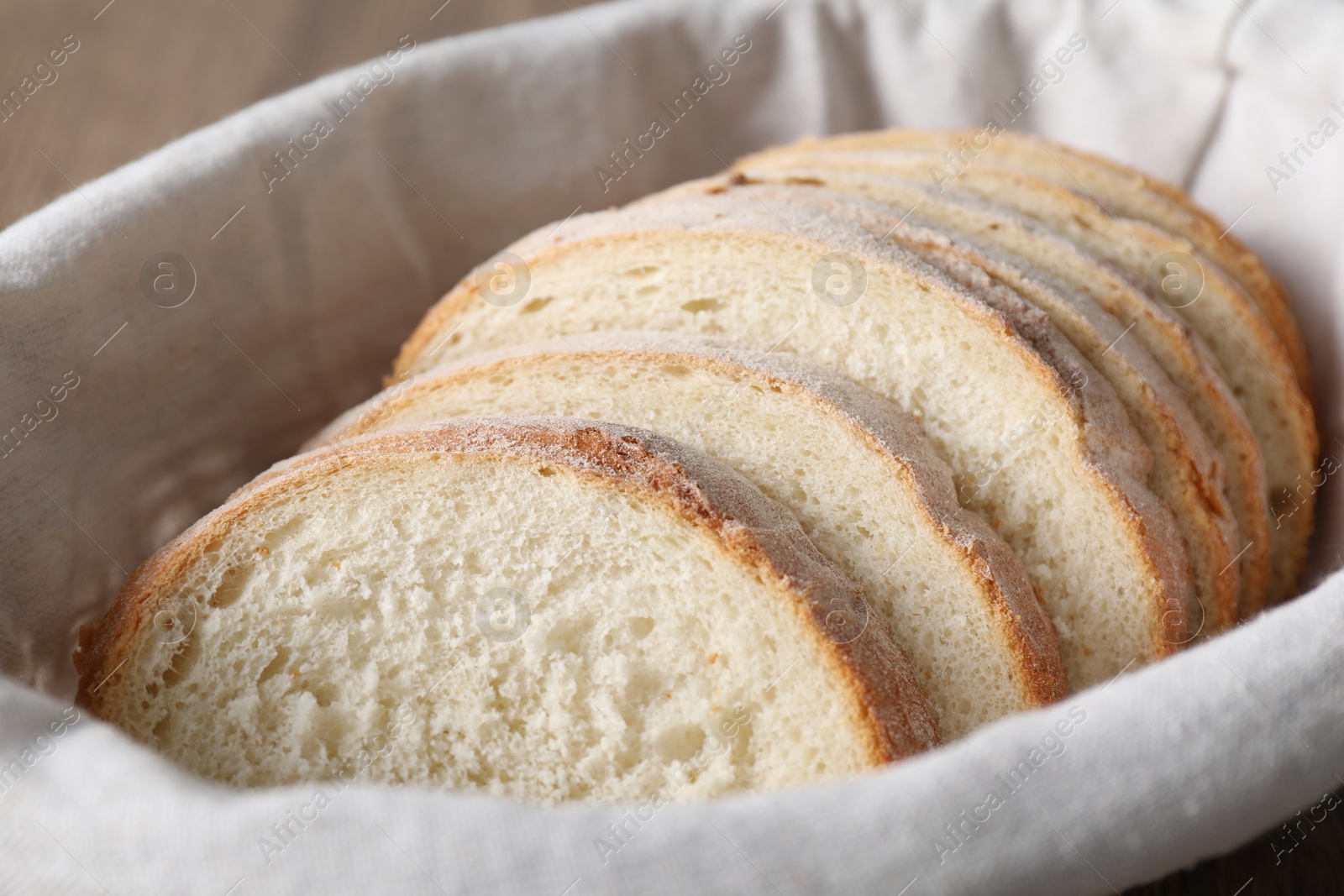 Photo of Slices of fresh bread on cloth in basket, closeup