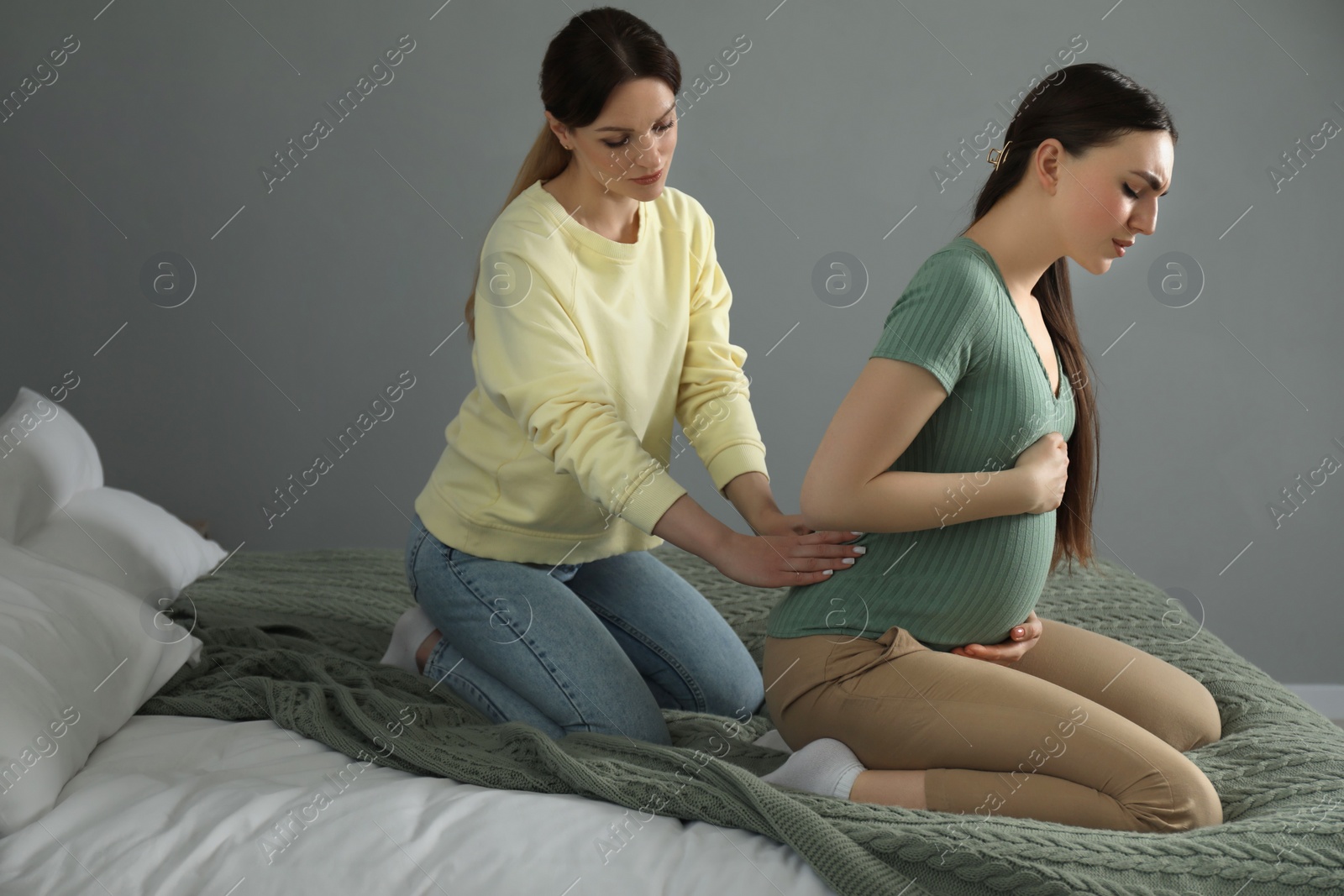 Photo of Doula massaging pregnant woman in bedroom. Preparation for child birth