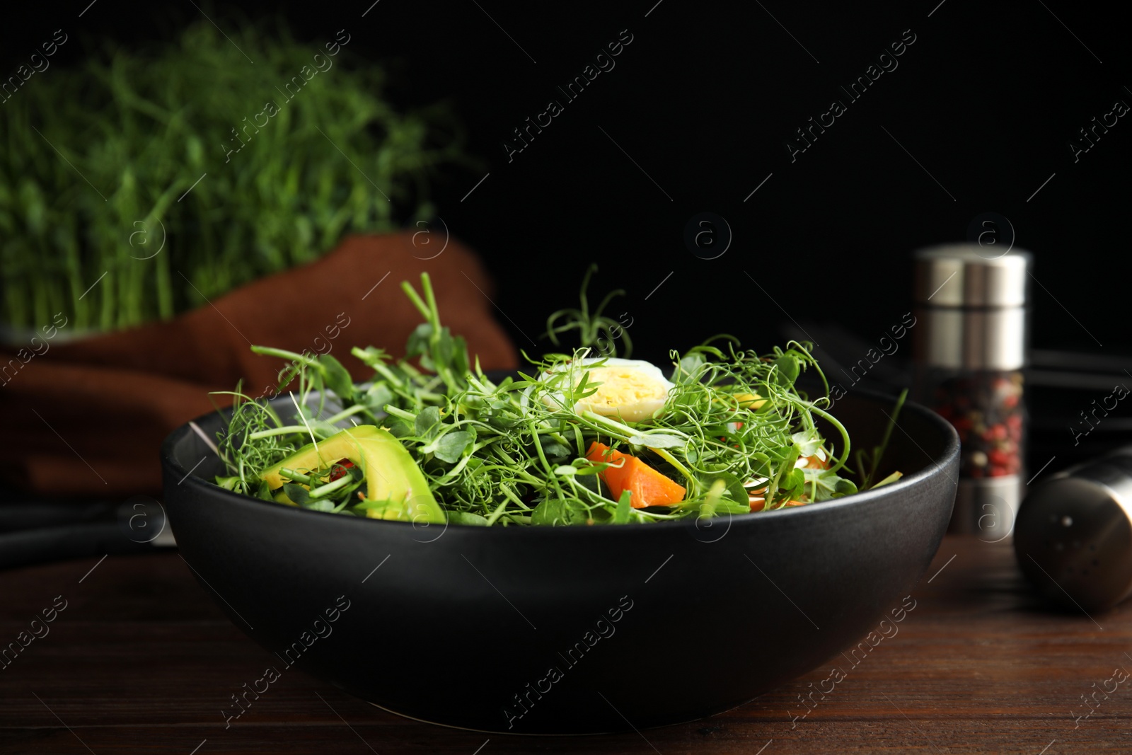 Photo of Salad with fresh organic microgreen in bowl on wooden table, closeup