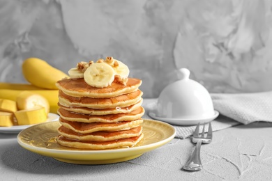 Stack of tasty pancakes with banana, nuts and honey on table