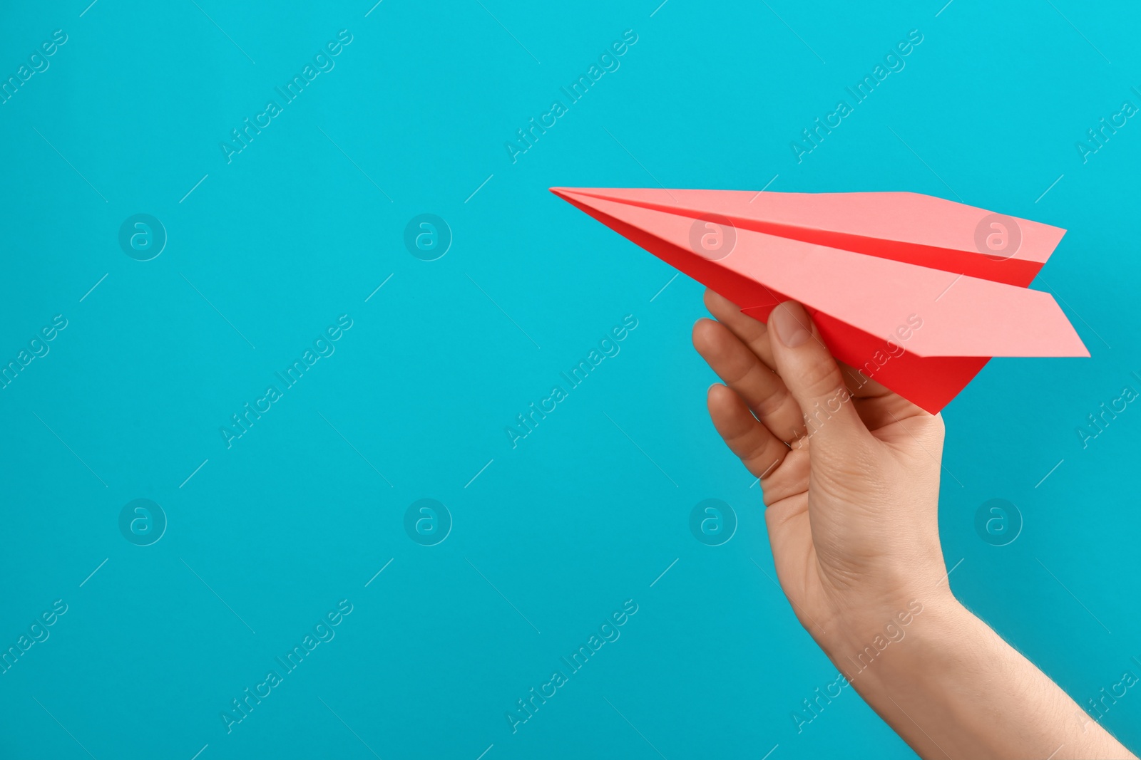 Photo of Woman holding paper plane on light blue background, closeup. Space for text