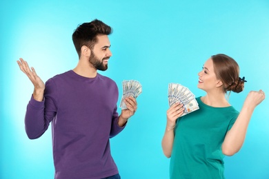 Happy young couple with money on color background