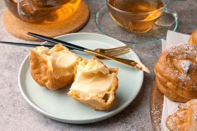 Delicious profiteroles filled with cream and tea on grey table