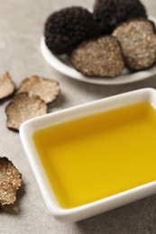 Bowl of truffle oil on light grey table, closeup