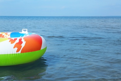 Photo of Bright inflatable ring floating on sea water. Space for text