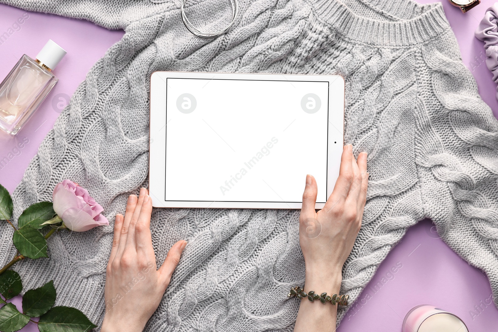 Photo of Woman with modern tablet and sweater on violet background, top view. Space for text