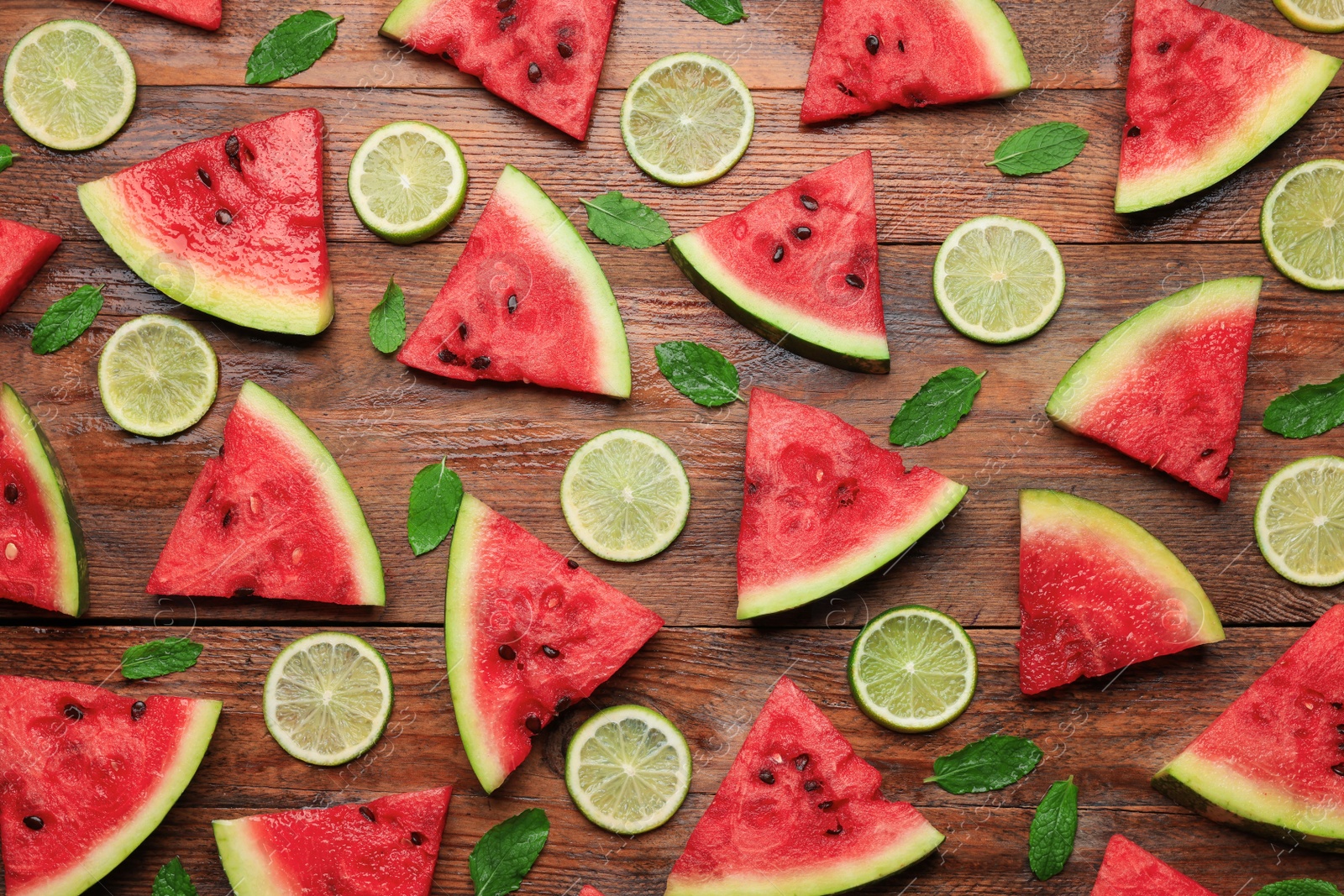 Photo of Tasty sliced watermelon and limes on wooden table, flat lay