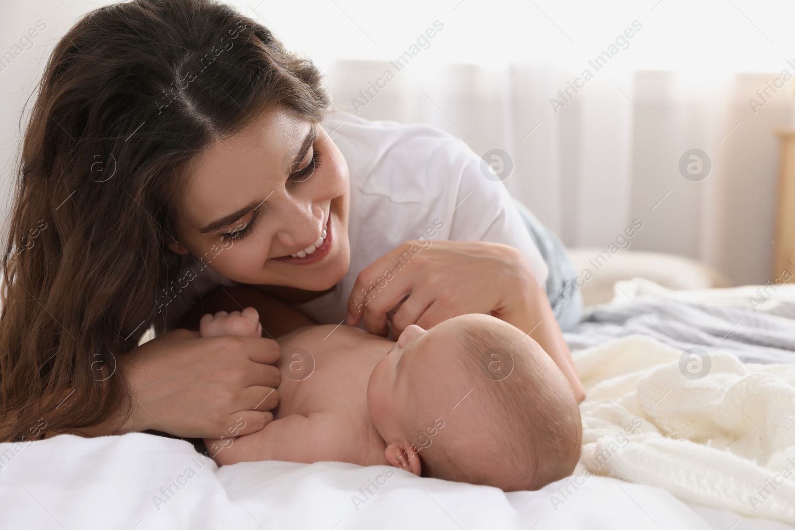 Photo of Happy young mother with her cute baby on bed at home