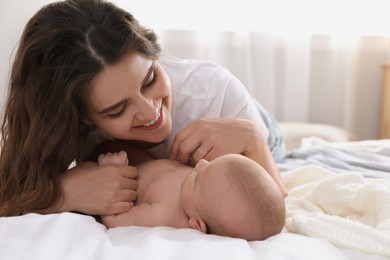 Photo of Happy young mother with her cute baby on bed at home