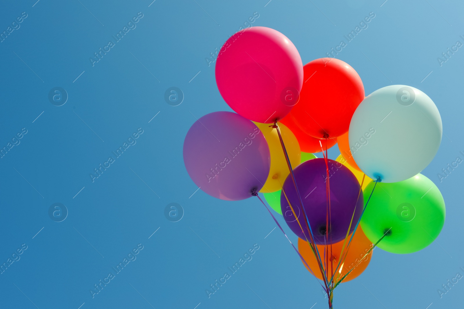 Photo of Bunch of colorful balloons against blue sky. Space for text