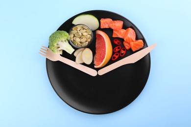 Photo of Metabolism. Plate with different food products and wooden cutlery on light blue background, top view