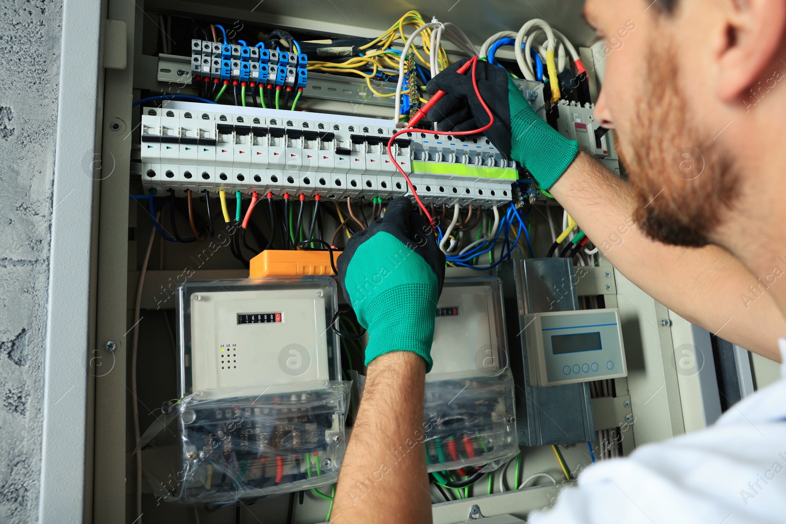 Photo of Electrician checking electric current with multimeter indoors, closeup