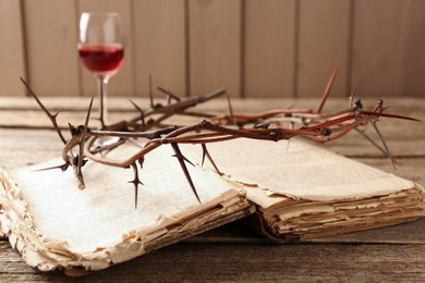 Photo of Crown of thorns, Bible and glass with wine on wooden table, selective focus