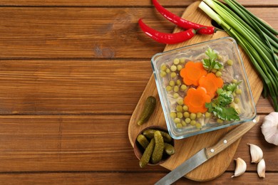 Photo of Delicious aspic with meat and vegetables served on wooden table, flat lay. Space for text