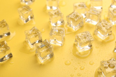 Crystal clear ice cubes on yellow background, closeup