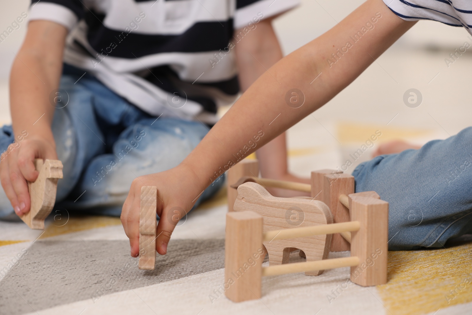 Photo of Little children playing with set of wooden animals indoors, closeup