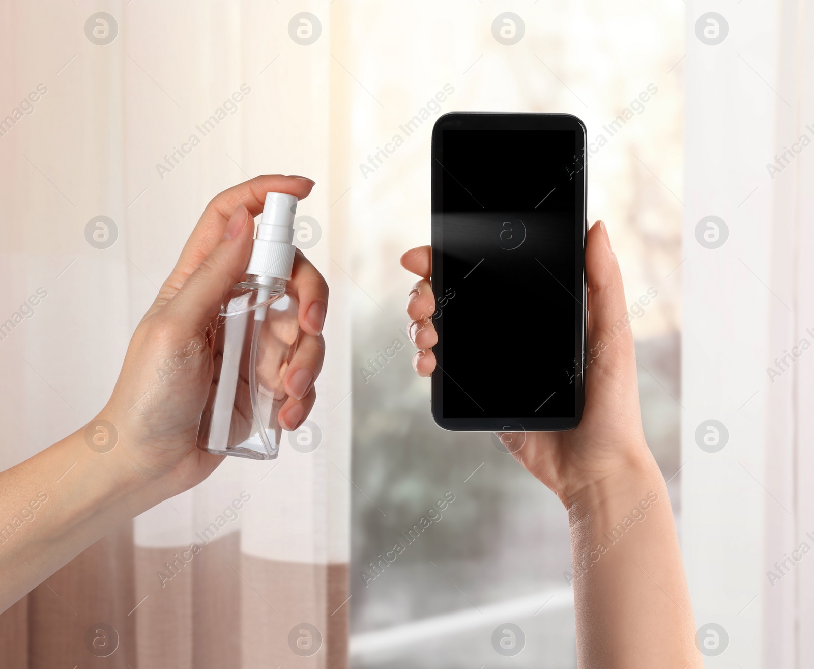 Image of Woman sanitizing smartphone with antiseptic spray indoors, closeup. Be safety during coronavirus outbreak 