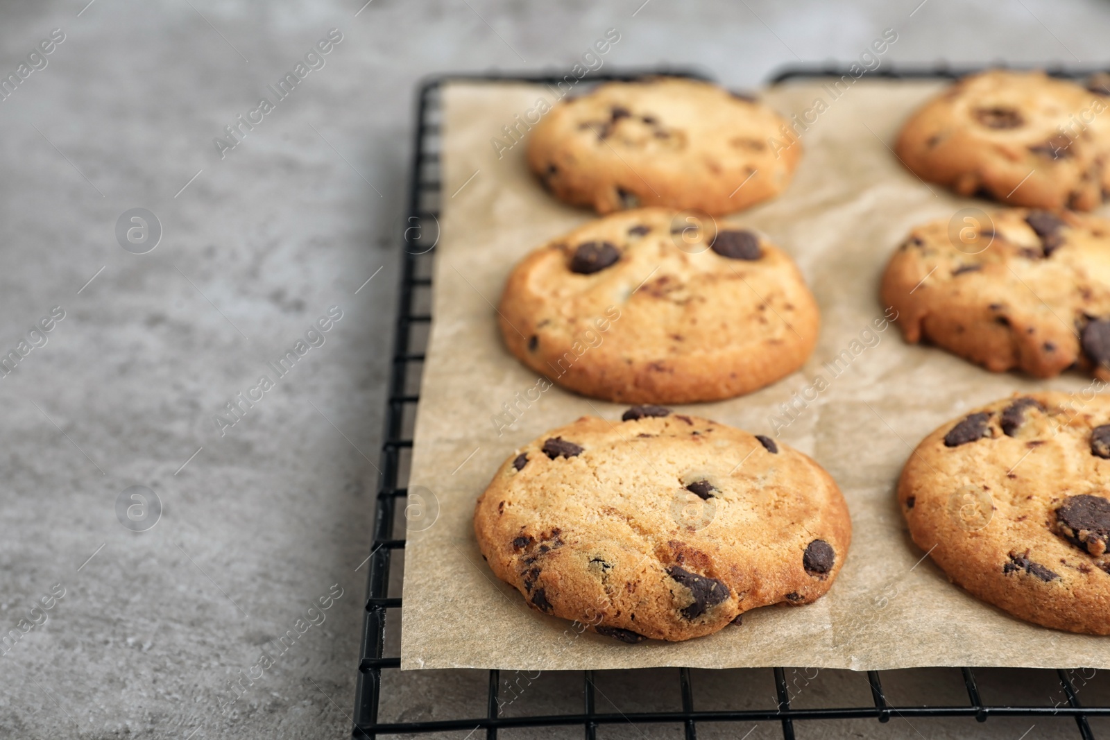 Photo of Cooling rack with tasty chocolate cookies on gray table