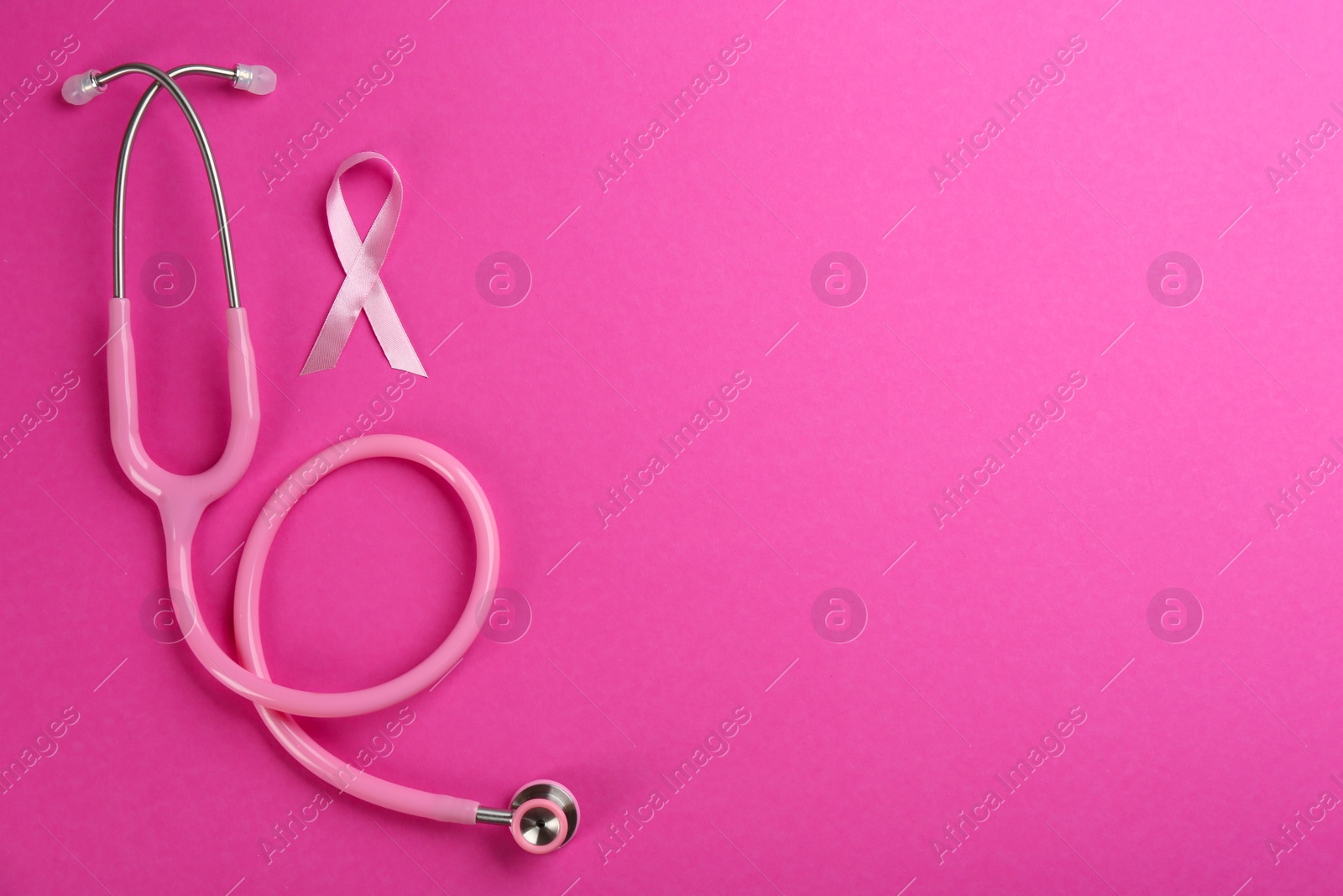 Photo of Pink ribbon as breast cancer awareness symbol and stethoscope on color background, flat lay. Space for text