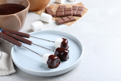 Photo of Tasty marshmallows dipped into chocolate on light grey marble table