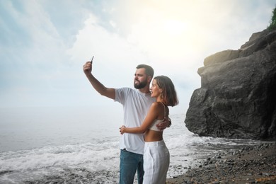 Photo of Happy young couple taking selfie on beach near sea