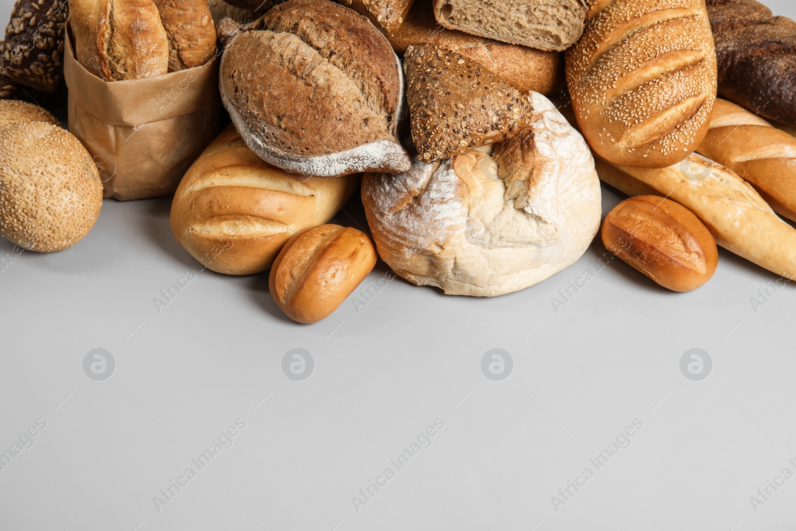 Photo of Pile of fresh tasty bread on light background