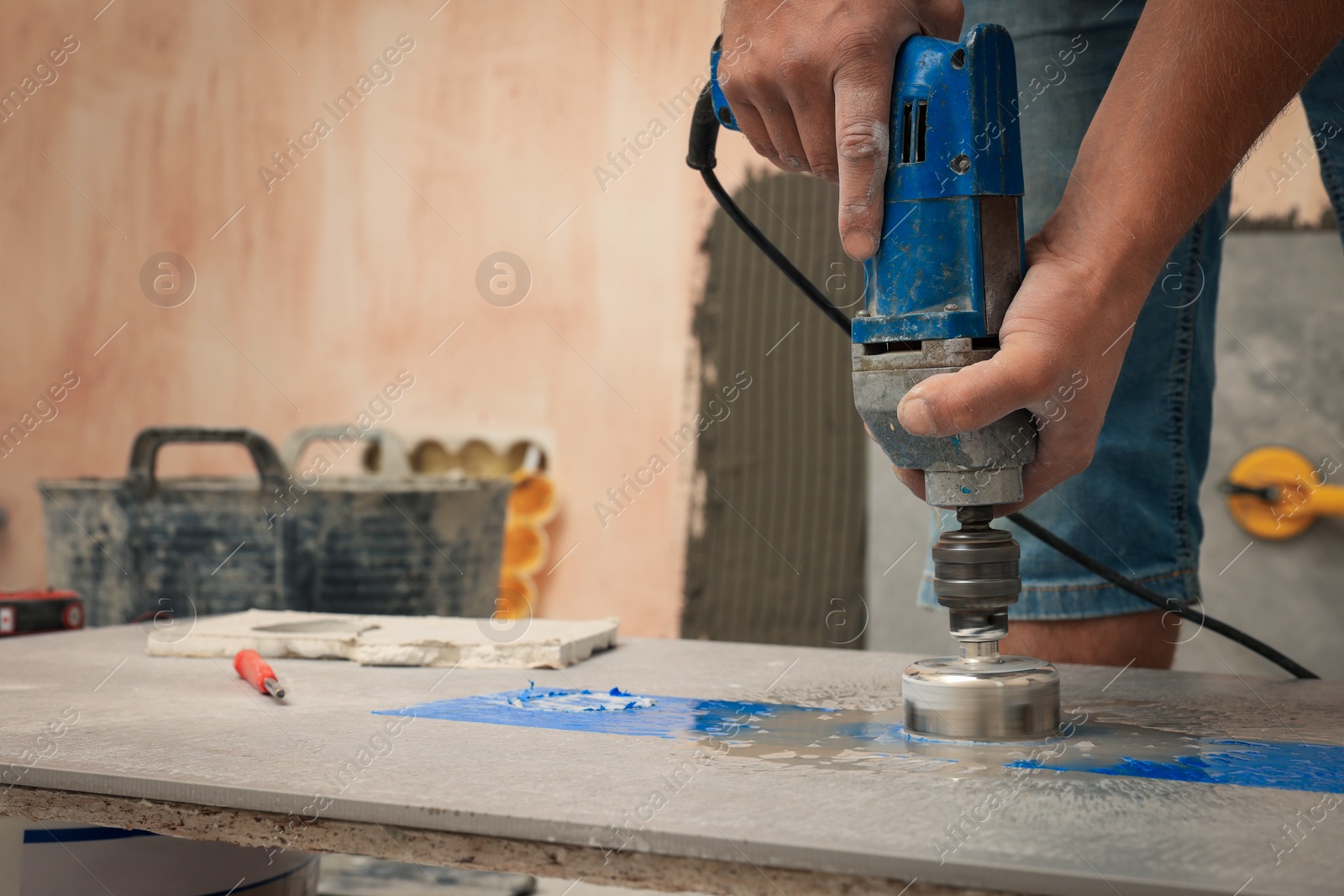 Photo of Worker making socket hole in tile indoors, closeup