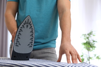 Man ironing shirt on board at home, closeup