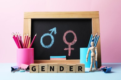Photo of Cubes with word Gender, stationery and chalkboard on color background