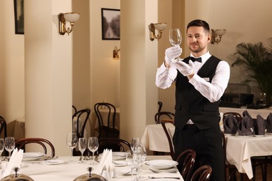 Photo of Man setting table in restaurant. Professional butler courses