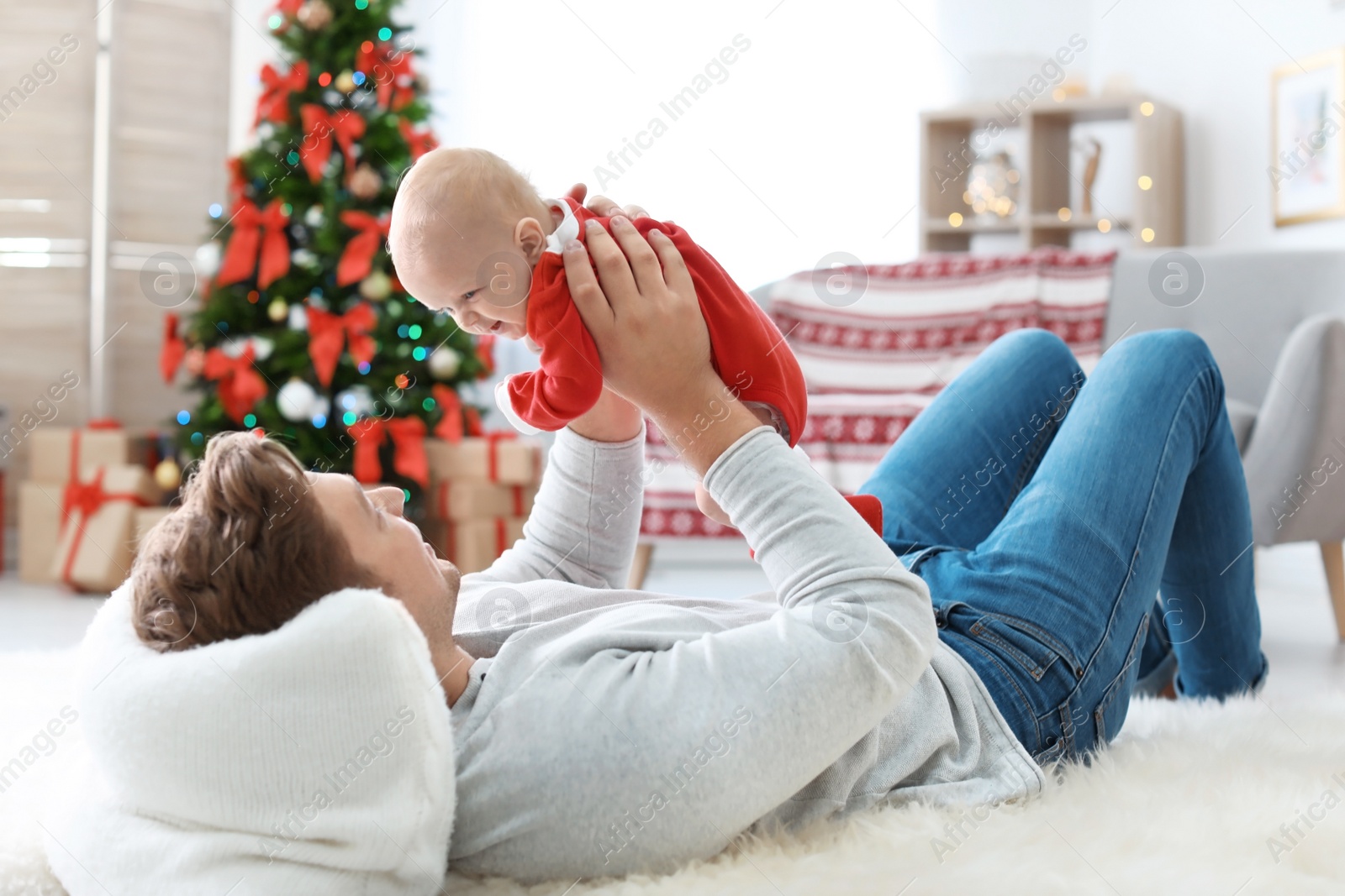 Photo of Young man with baby in Christmas suit at home