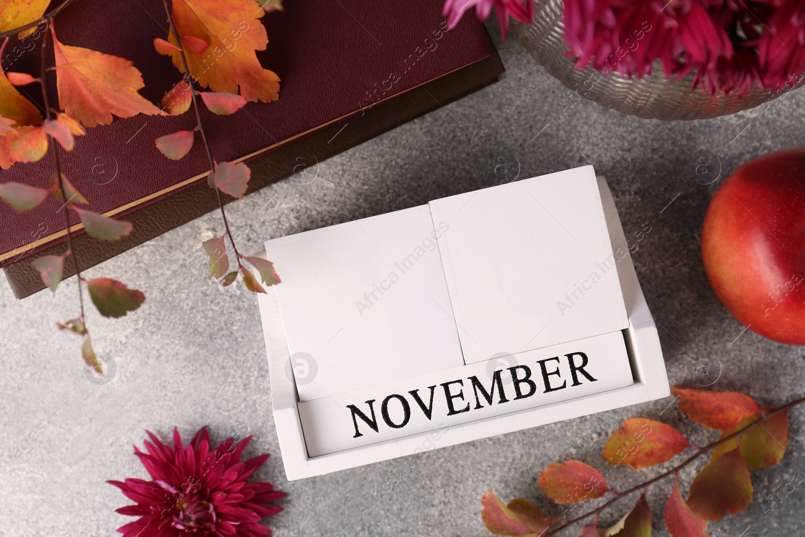 Photo of Thanksgiving day, holiday celebrated every fourth Thursday in November. Flat lay composition with wooden block calendar and autumn leaves on grey table