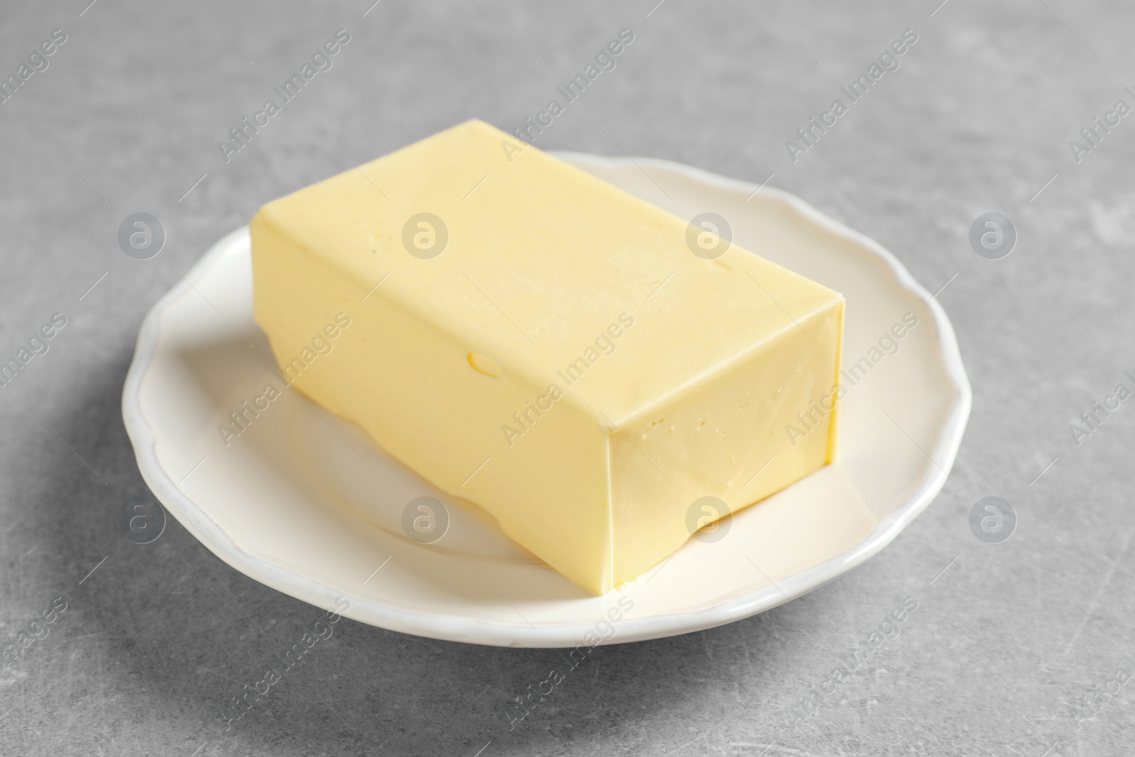 Photo of White plate with fresh butter on table