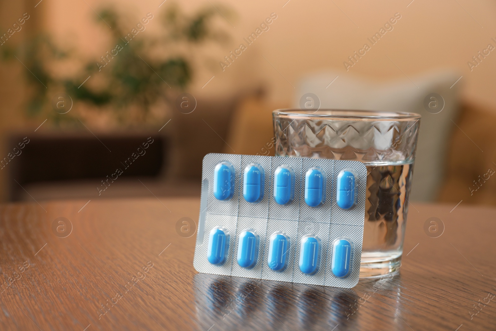 Photo of Glass of water and pills on wooden table indoors, space for text. Potency problem concept