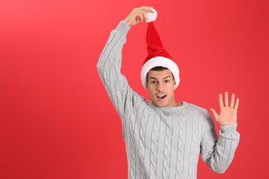 Photo of Surprised man wearing Santa hat on red background, space for text