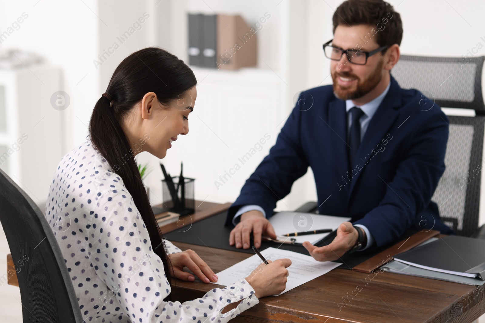 Photo of Woman signing document in lawyer's office, selective focus