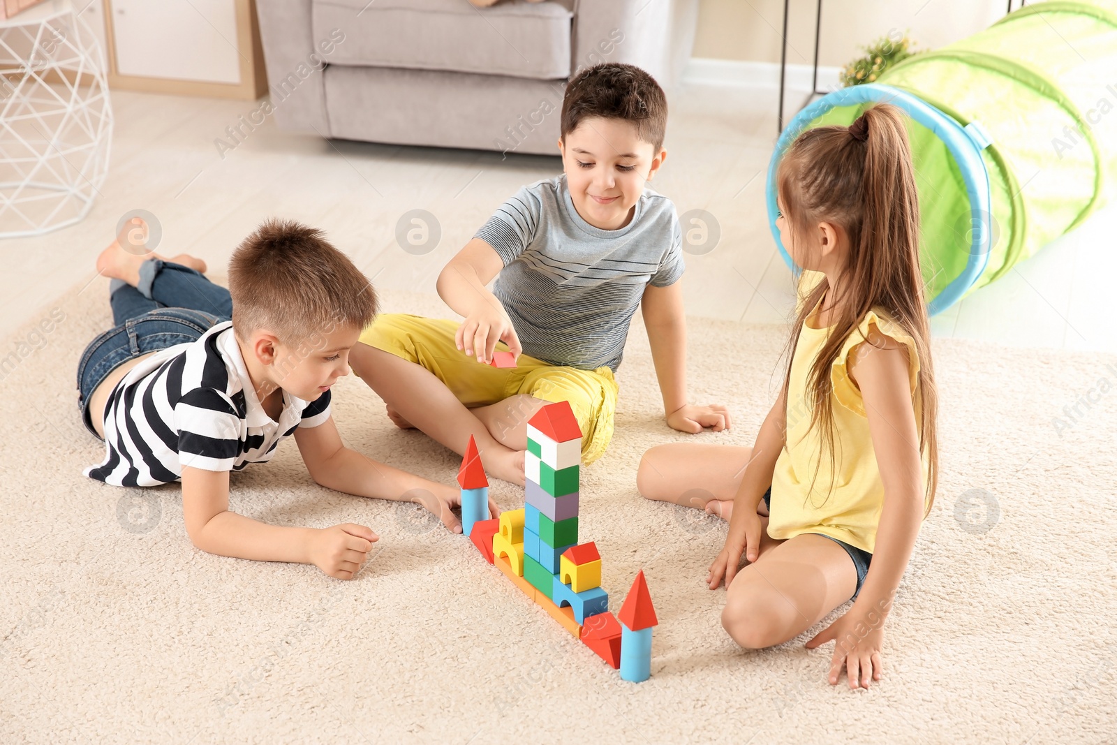 Photo of Cute little children playing with building blocks on floor, indoors