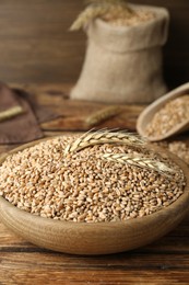 Photo of Bowl with wheat grains on wooden table