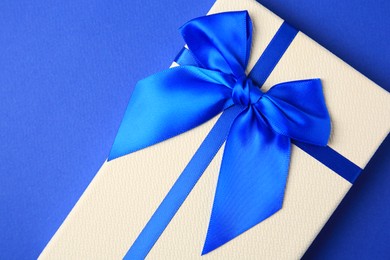 Photo of Beautiful gift box with bow on blue background, top view