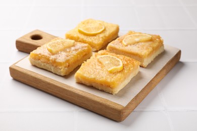 Tasty lemon bars on white tiled table, closeup