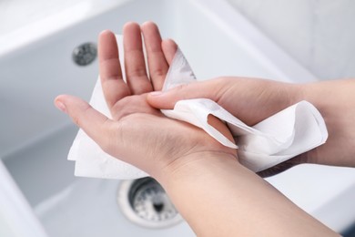 Photo of Man wiping hands with paper towel above sink, closeup