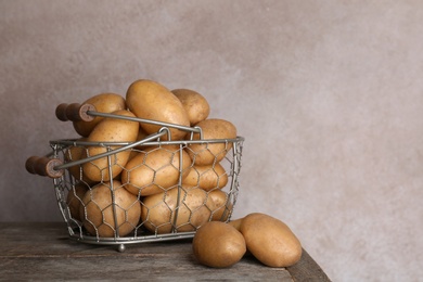 Basket with fresh ripe organic potatoes on wooden table