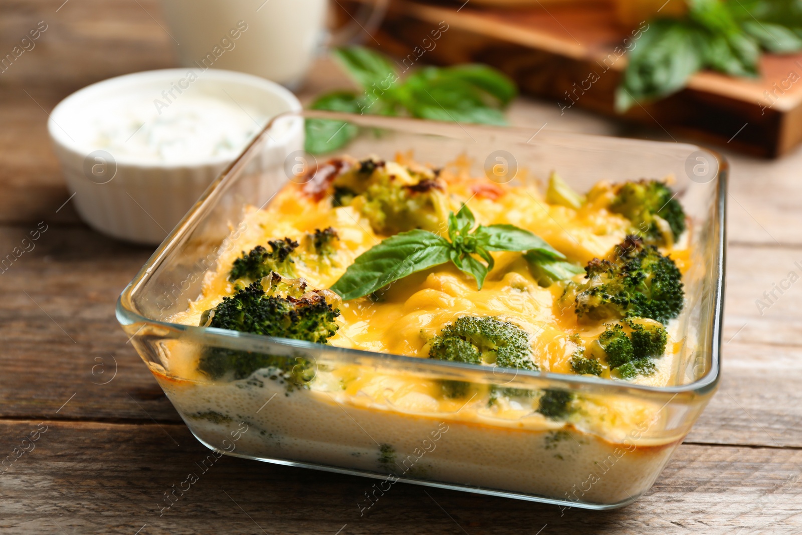 Photo of Tasty broccoli casserole in baking dish on wooden table